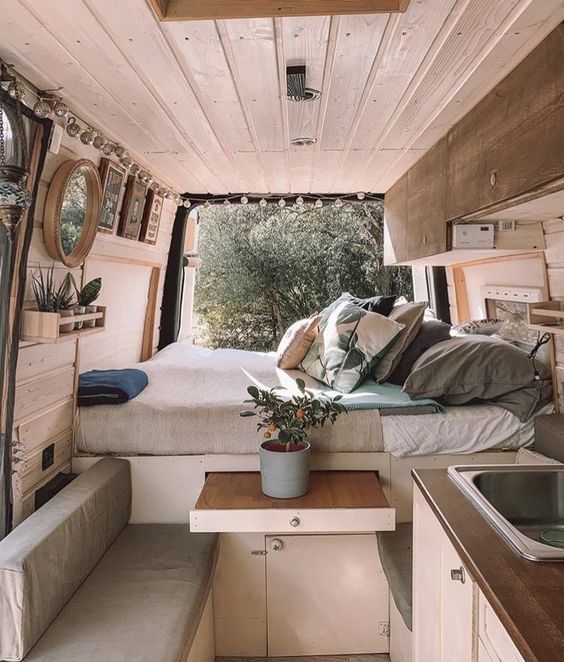 intérieur d'un van aménagé avec un lit et une table avec banquette